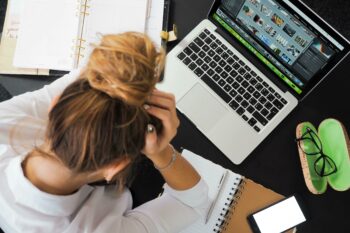 Woman with her head in hands looking at a laptop