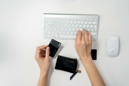Personal holding card by laptop, ready to set up electronic payment for a recurring service. This will help the business with cash flow management
