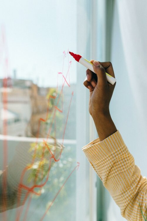 Woman drawing graph on glass, working out how to scale while saving time and money