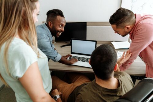 Team of casually dressed workers smiling because of changing culture in the company